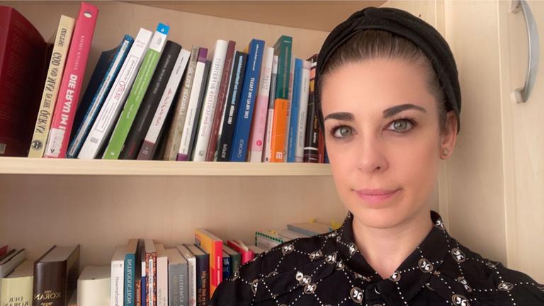 Dina El Omari steht vor einem Bücherregal. Dina El Omari steht vor einem Bücherregal.